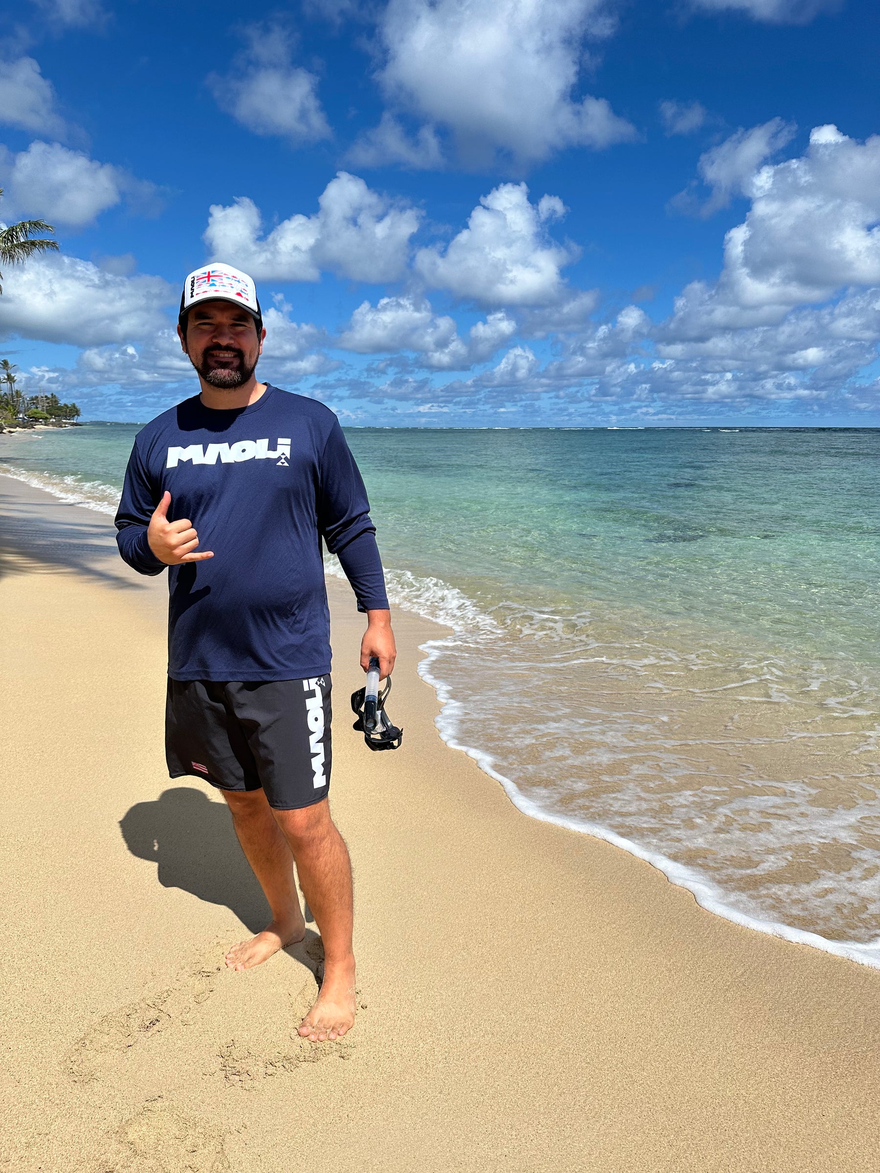 Man standing on the shore with Maoli ocean apparel and a snorkel